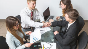 Quatro pessoas reunidas em uma mesa para fechar negócios.