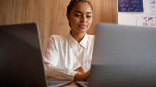 Mulher em frente de dois notebooks trabalhando como advogada online.